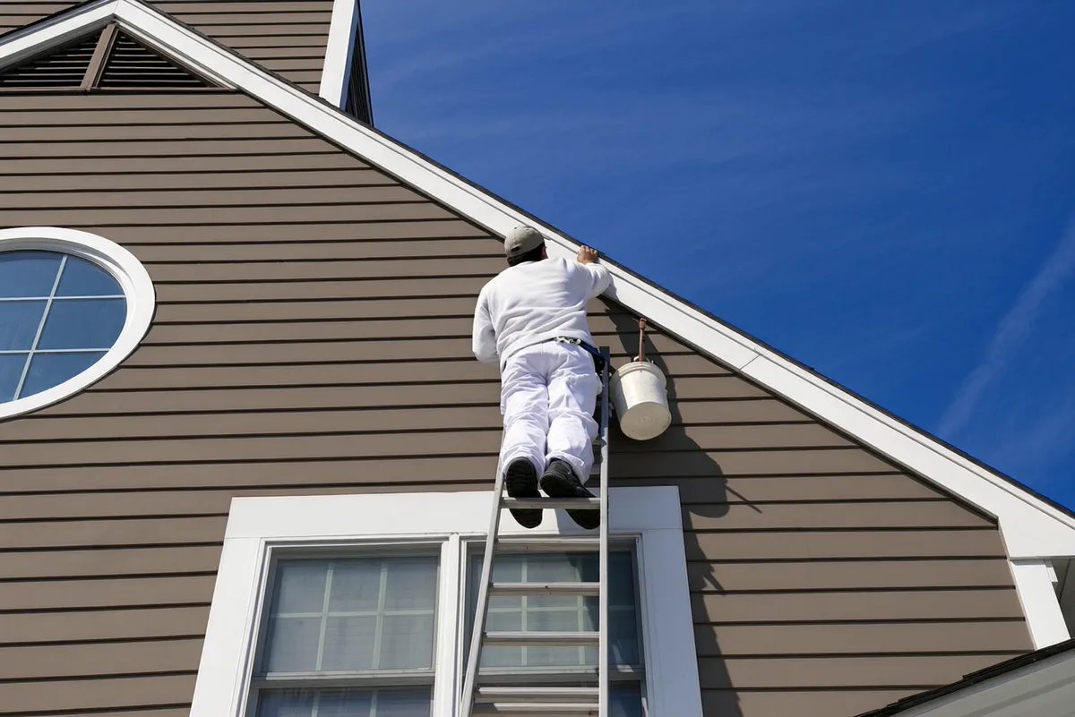 Extension ladder set against a house gable during exterior painting
