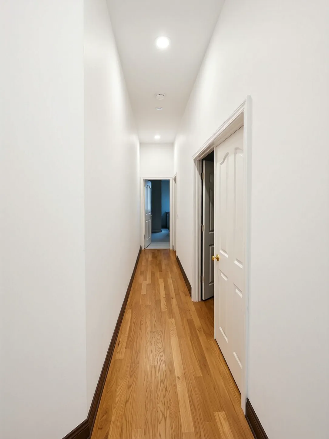 Repainted hallway with white baseboards, door casing and warm neutral walls